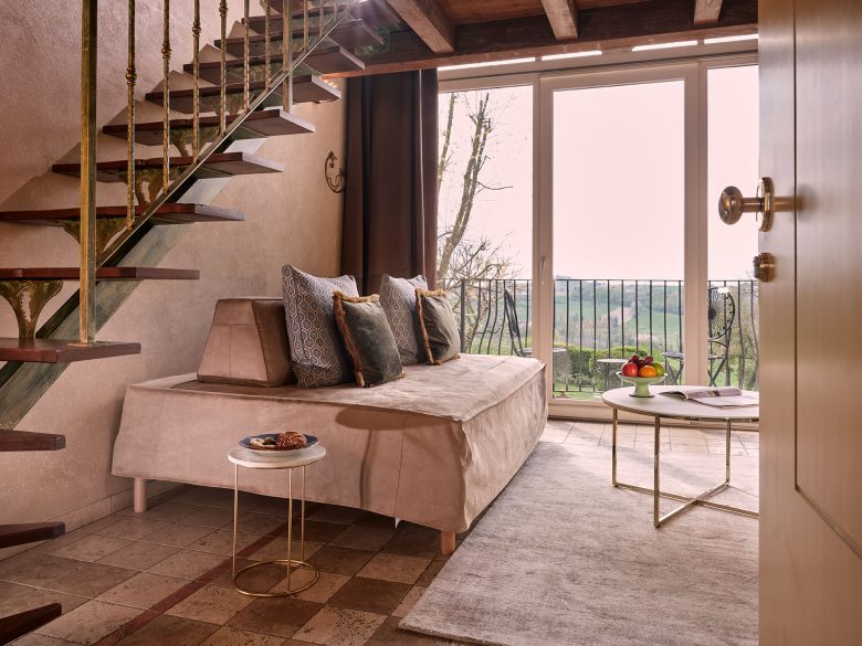 Elegant suite at TM Relais, overlooking scenic countryside views with chic furniture and large windows.