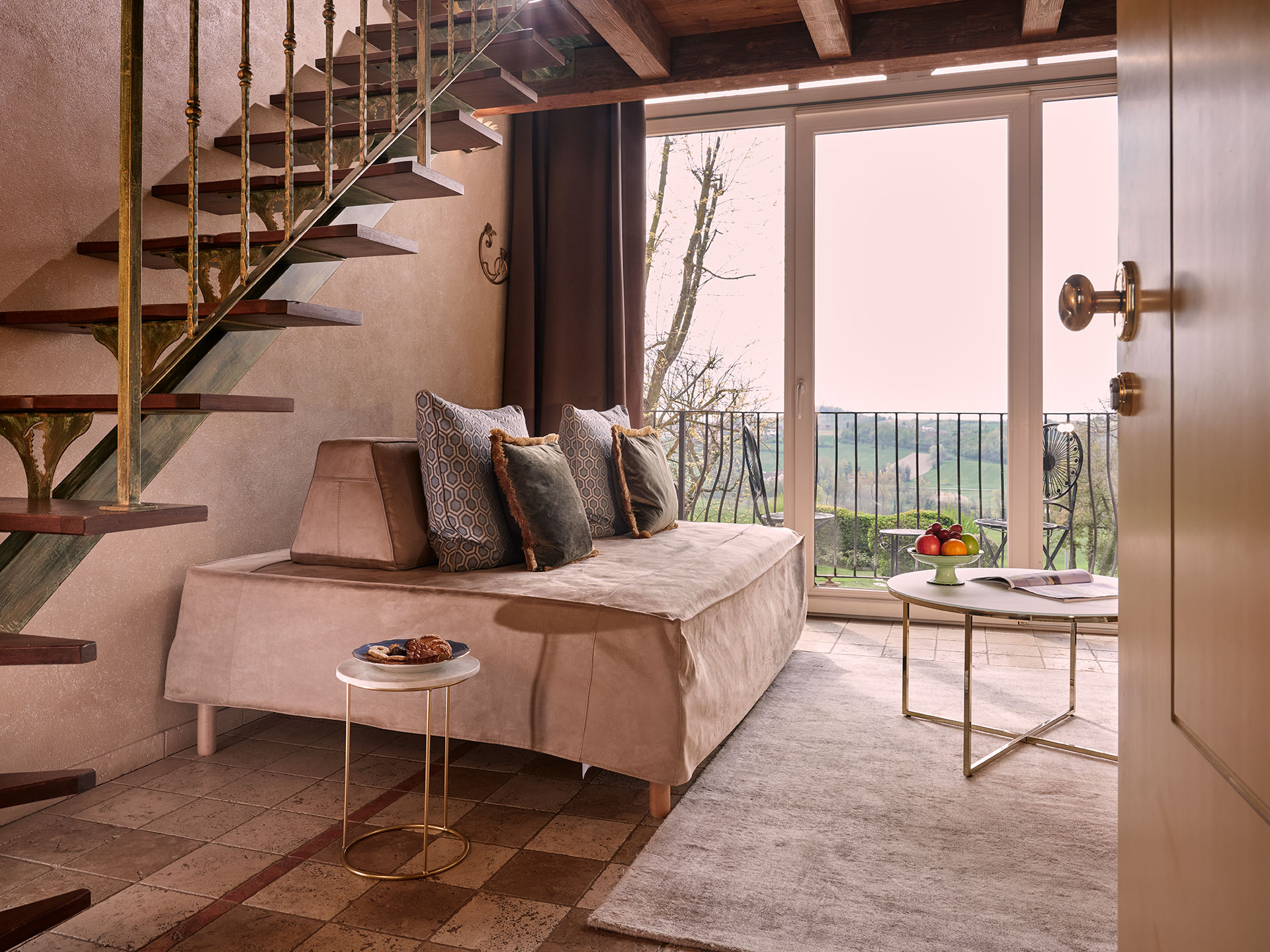 Elegant suite at TM Relais, overlooking scenic countryside views with chic furniture and large windows.