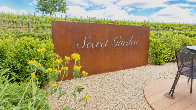 Secret Garden at TM Relais estate, surrounded by lush vineyards and vibrant flowers, offering luxury hospitality.