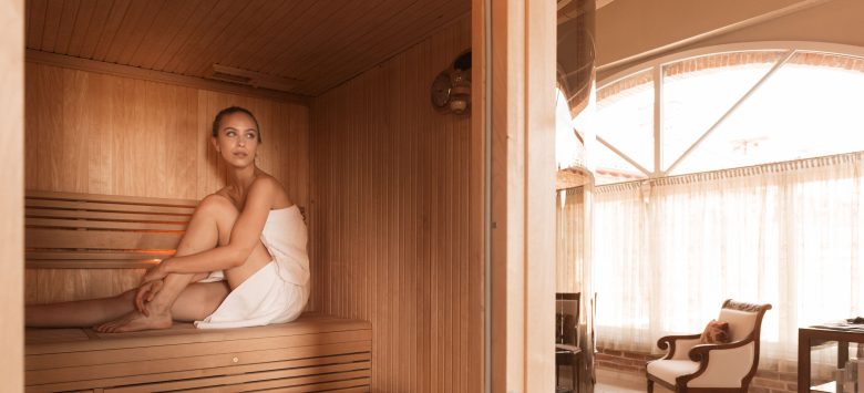 Woman relaxing in a luxurious sauna at TM Relais estate, offering high-quality hospitality.