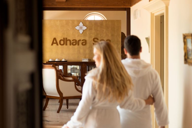 Couple in white robes entering Adhara Spa at TM Relais, a luxury hospitality estate in Italy.